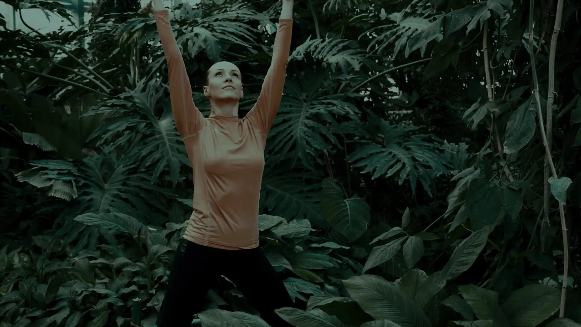 Frau steht in Yogapose in einem Urwald