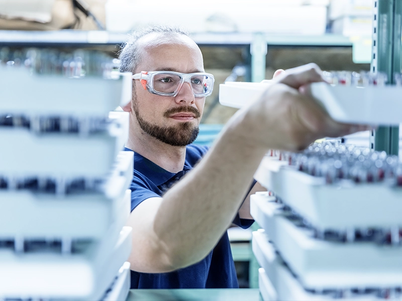 Das Foto aus dem Shooting für die EuroSprinklers Corporate Website zeigt einen Mitarbeiter, der ein Tablett voller Sprinkler einräumt. Es ist ein prägendes Bild der EuroSprinklers Markenkommunikation, das die Präzision und Effizienz in der Herstellung der Produkte hervorhebt.